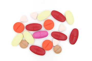 Detailed photos of oval, round and triangular shaped tablets in various colors: red, orange, yellow and cream. The photo was taken on a white background