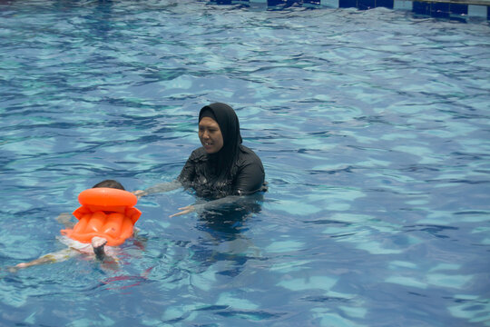 A mother teaches her toddler how to swim - Powered by Adobe