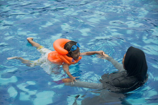 A mother teaches her daughter how to swim - Powered by Adobe