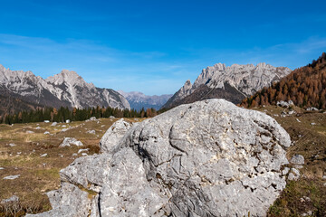 Fototapeta na wymiar Rock formation on golden colored alpine meadows and forest in autumn. Scenic view of majestic mountains of Carnic Alps, Sauris di Sopra, Friuli Venezia Giulia, Italy. Tranquil atmosphere Italian Alps