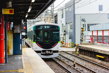 Local train, railcar arrive to railway station platform in rainy day in Japan. - obrazy, fototapety, plakaty