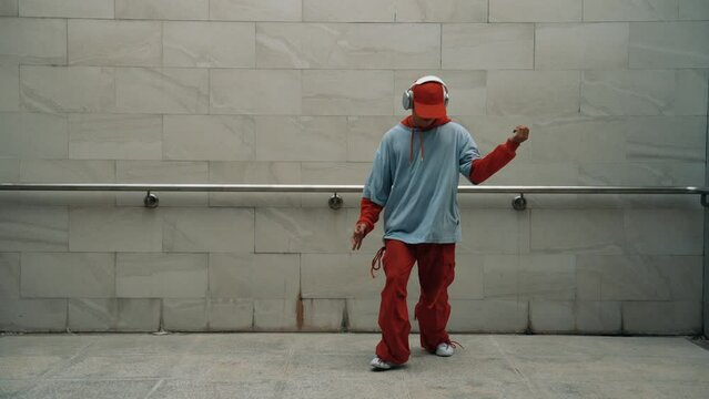 Handsome choreographer practice street dance in gray background. Young attractive b boy dancer perform while wearing stylish cloth. Feeling of lively step. Copy space. Outdoor sport 2024. Sprightly.