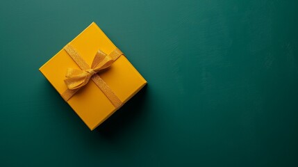 A compact mustard yellow square folding gift box, half-closed, on a deep seafoam green background.