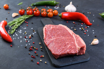 Raw fresh marbled meat and seasonings on dark background