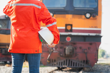 Close-up at a worker is holding white safety helmet, posing on crude oil tanker freight train as...