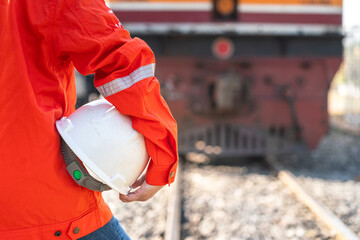 Close-up at a worker is holding white safety helmet, posing on crude oil tanker freight train as...