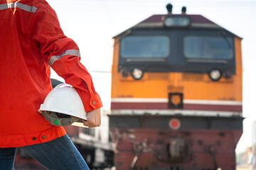 Close-up at a worker is holding white safety helmet, posing on crude oil tanker freight train as...