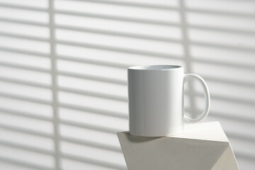 White cup on stand in sunlight on gray background close up