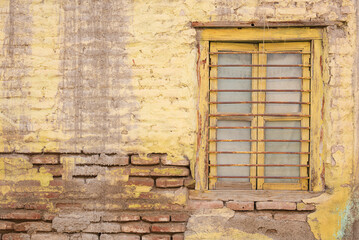 Yellow color old wooden window on a brick textured wall