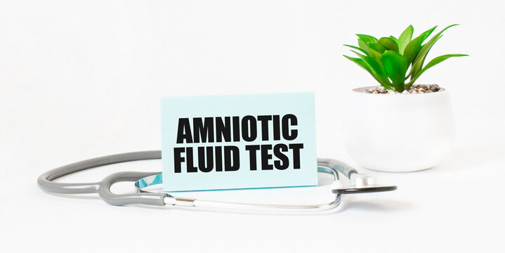 AMNIOTIC FLUID TEST word on notebook, stethoscope and green plant