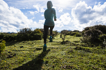 Woman trail runner cross country running at high altitude mountain peak