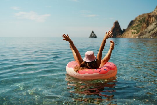 Summer vacation woman in hat floats on an inflatable donut mattress. Happy woman relaxing and enjoying family summer travel holidays travel on the sea.