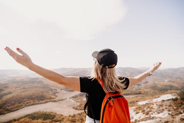 woman backpack on mountain peak looking in beautiful mountain valley in autumn. Landscape with sporty young woman, blu sky in fall. Hiking. Nature