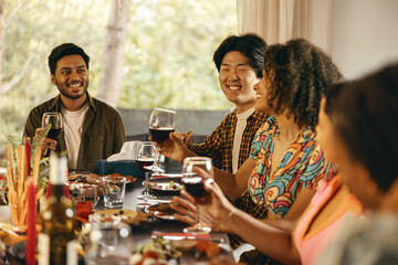 Happy friends enjoying in conversation and drinking wine during festive dinner at home party