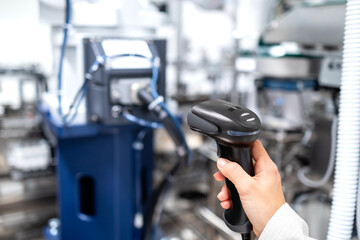 Worker holding bar code scanner at production line in factory.