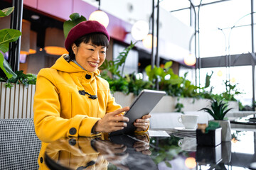 Female businesswoman in cafe bar using tablet computer at airport lobby before flight.