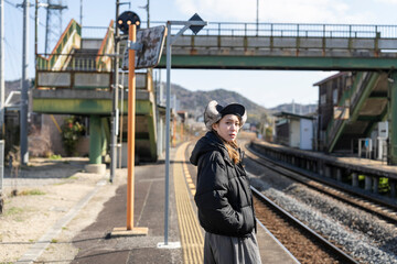 田舎の駅のホームで電車を待つ女性