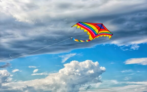 rainbow kite flying in blue sky with clouds in summer with copyspace