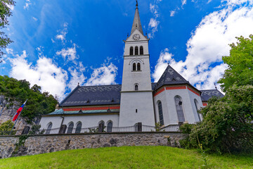 Fototapeta na wymiar Scenic view of white St. Martin's Parish Church at lakeshore of Lake Bled on a cloudy summer day. Photo taken August 8th, 2023, Bled, Slovenia.