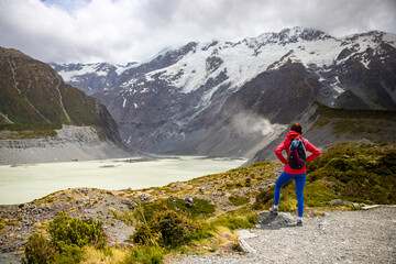 Naklejka premium hiker girl walking alongside hooker valley track toward hooker lake and mt cook, famous walk in canterbury, new zealand south island