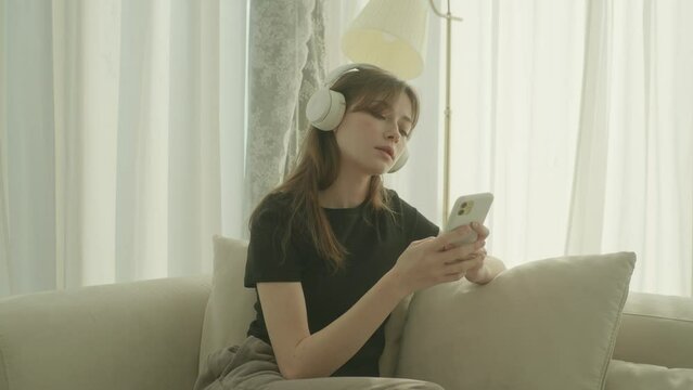 Young woman looking at her phone and listening to music