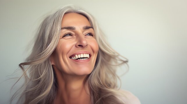 Portrait of mature woman with gray hair laughing and smiling. Gorgeous beautiful mature lady with fine wrinkles.