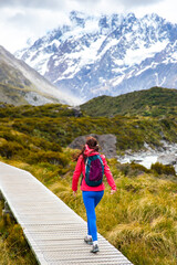 Naklejka premium hiker girl walking alongside hooker valley track toward hooker lake and mt cook, famous walk in canterbury, new zealand south island