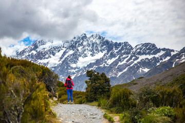 hiker girl walking alongside hooker valley track toward hooker lake and mt cook, famous walk in canterbury, new zealand south island