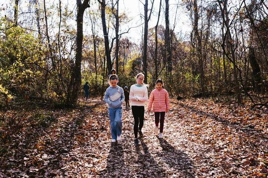 Family with girls in front hike in sunshine in fall and autumn forest