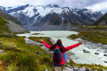 hiker girl walking alongside hooker valley track toward hooker lake and mt cook, famous walk in...