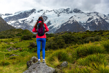 Obraz premium hiker girl walking alongside hooker valley track toward hooker lake and mt cook, famous walk in canterbury, new zealand south island