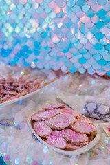 Pink sprinkles on pink iced cookies with blue scale backdro