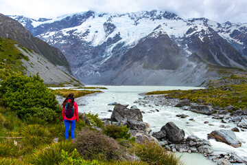 hiker girl walking alongside hooker valley track toward hooker lake and mt cook, famous walk in...