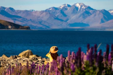 Cercles muraux Aoraki/Mount Cook beautiful girl in yellow dress and hat standing on the field of colorful lupins and enjoying the sunset over lake tekapo  unique flowers near mountaineous lake in new zealand, south island, canterbury
