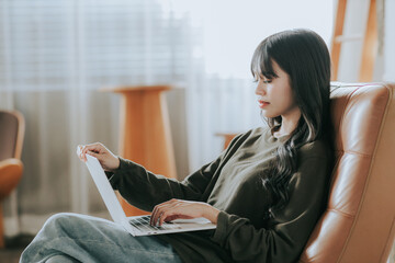 Image of a beautiful, cute, cheerful, happy Asian woman sitting in a cafe. using a laptop computer