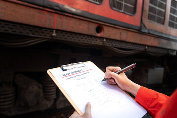 A technician is checking on heavy machine maintenance checklist, with train locomotive engine cabin...