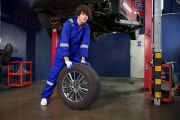 mechanic holding and pushing a tire for fixing in garage