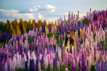 Crédence de cuisine en verre imprimé Aoraki/Mount Cook beautiful girl in yellow dress enjoying a walk in the field of lupins on sunset  colorful flowers of lupins blooming near lake pukaki, canterbury, new zealand