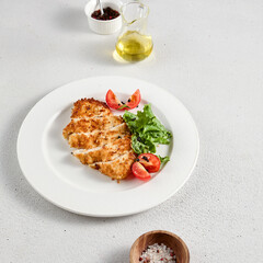 Golden crusted chicken fillet with cheese on a bed of lettuce, topped with cherry tomatoes, ideal for recipes and menu designs