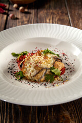 Baked eggplant roll with cheese and tomatoes, elegantly plated on a white dish