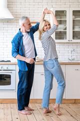 Mature married couple dancing with smile on kitchen
