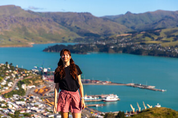 Fototapeta na wymiar pretty hiker girl enjoying the panorama of lyttelton after finishing the hike on the bridle path from christchurch to lyttelton; beautiful view from gondola summit station, canterbury, new zealand 
