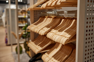 Obraz na płótnie Canvas Many empty wooden hangers for clothes on shop store rack