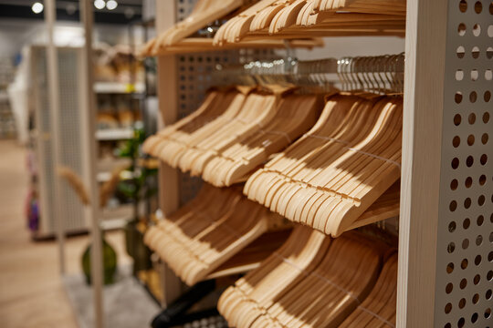 Many empty wooden hangers for clothes on shop store rack