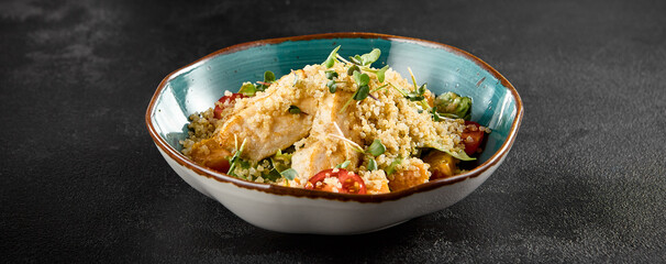 Quinoa salad with grilled chicken, cherry tomatoes, and greens in a turquoise ceramic bowl