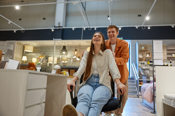Overjoyed young family couple fooling around at furniture store
