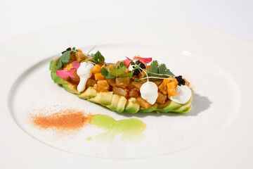 Avocado and tuna tartare on a chic white plate sprinkled with paprika, an exquisite choice for stylish vegetarian starters