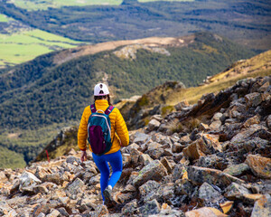 hiker girl walking down the steep trail from the top of mount somers in canterbury, new zealand...