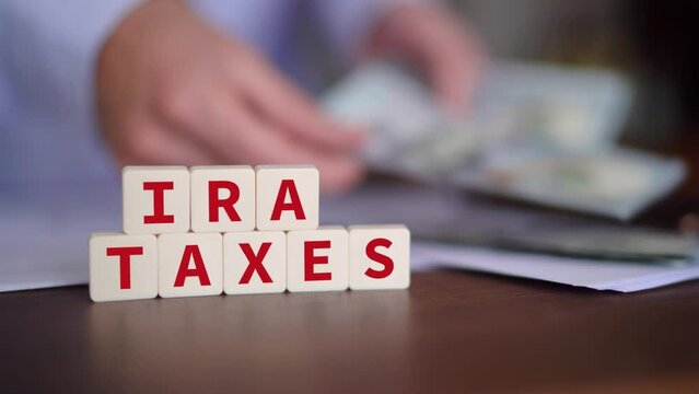 Concept of paying taxes of your Individual Retirement Account. IRA taxes word with selective focus and person paying on the background.