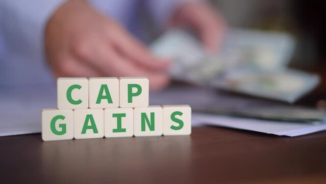 Concept of Capital Gains. Cap gains word with selective focus and person paying on the background.